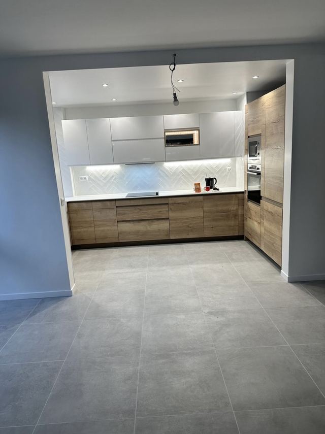 Cuisine après aménagement : meubles bas bois, meubles hauts blancs, crédence blanche à chevrons et carrelage grand format